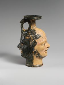 Etruscan vase formed formed from two sculpted black and yellow jainform heads.