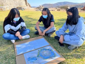 Three Nahua youth sit around a map of Tenochtitlan.